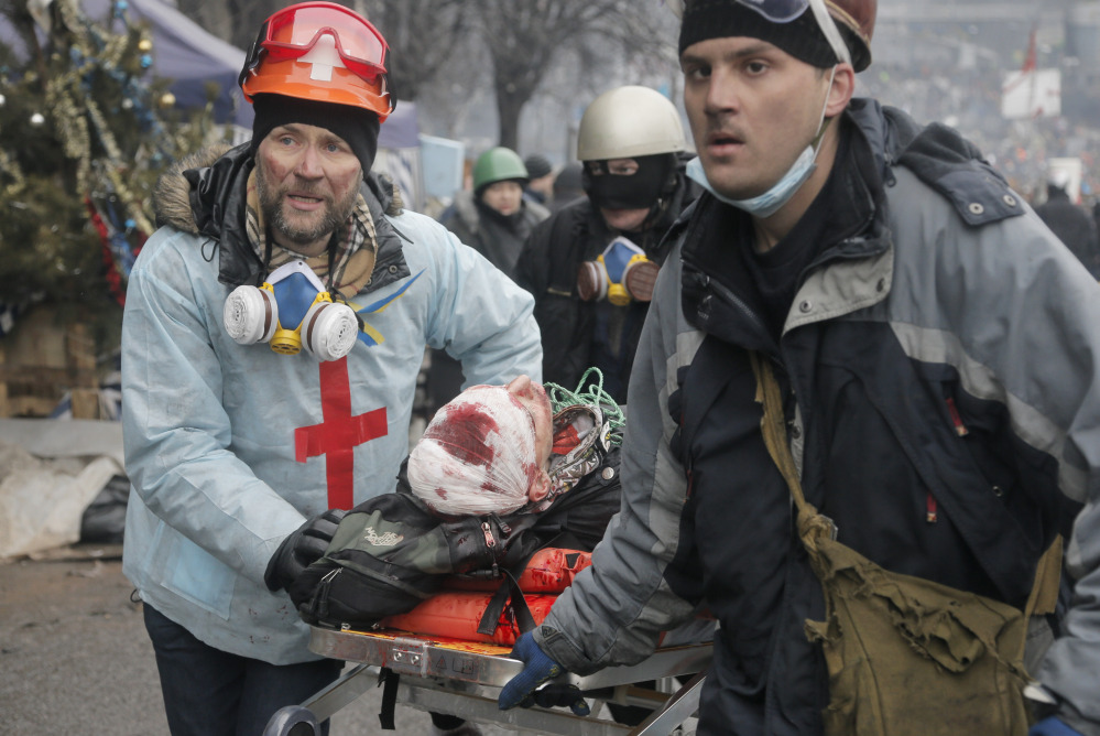Activists evacuate a wounded protester during clashes with police in Kiev’s Independence Square on Feb. 20. An investigation is trying to determine who was behind attacks by rooftop snipers.