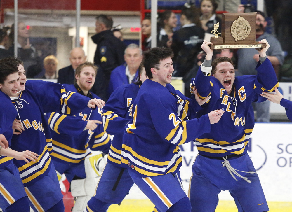 Jake Grade joins Andre Clement (with trophy) and teammates in the celebration Saturday after Falmouth defeating St. Dominic Academy 3-2 in overtime to win the Class A boys’ hockey state Championship at the Colisee in Lewiston.