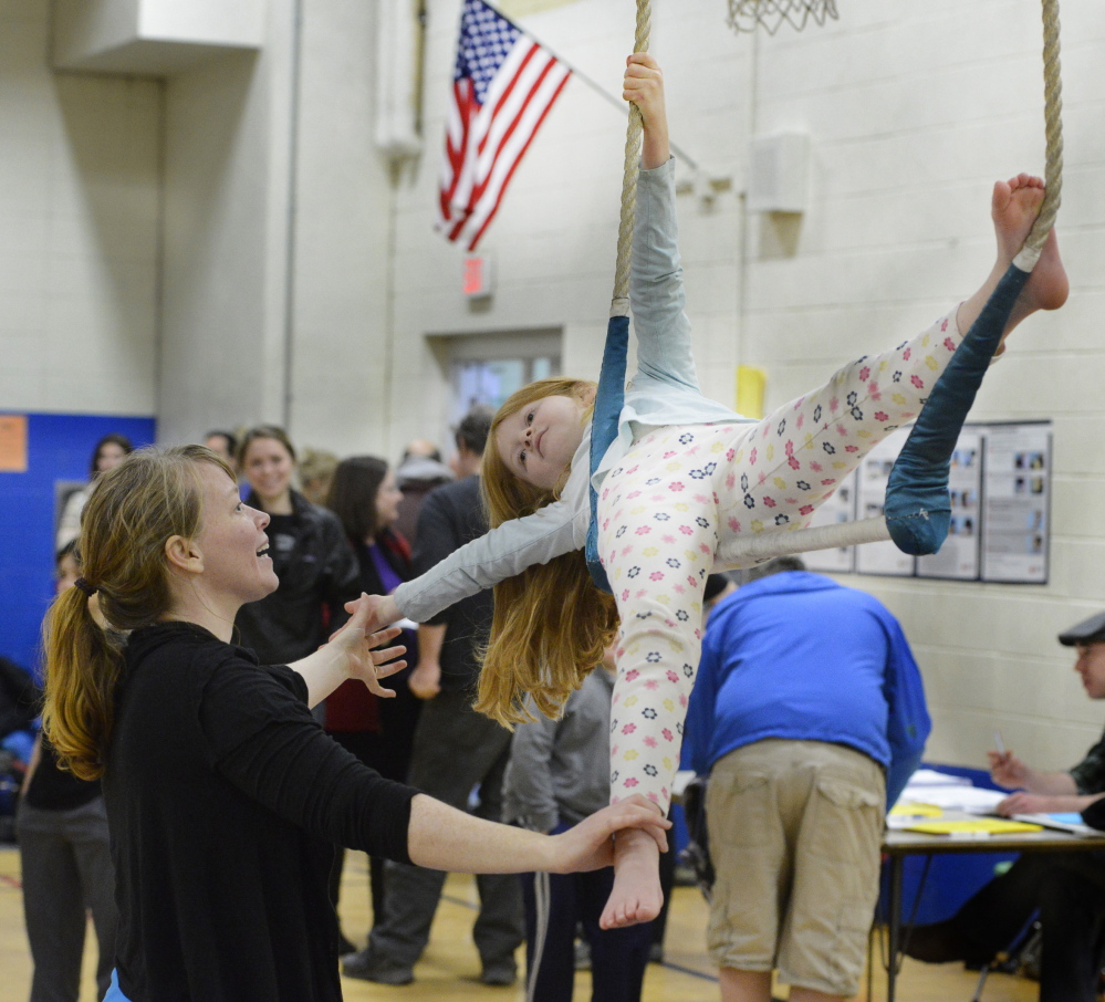 Aerials coach Jeanette Fertig works with Norah Peabey, 8, of Portland on the trapeze during Circus Atlantic’s an open house at Reiche Community School in Portland on Saturday.