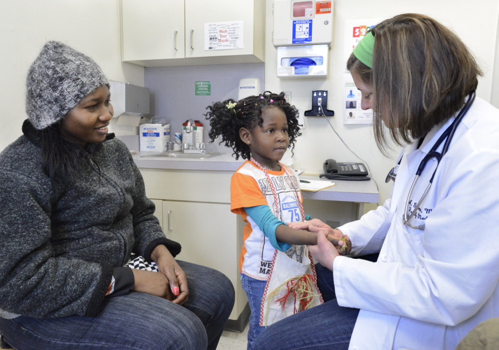 Fineza Mawaba of Portland, originally from Angola, watches her daughter Dadina, 4, get a tuberculosis test reading from Dr. Alison Gorman at Portland Community Health Center.