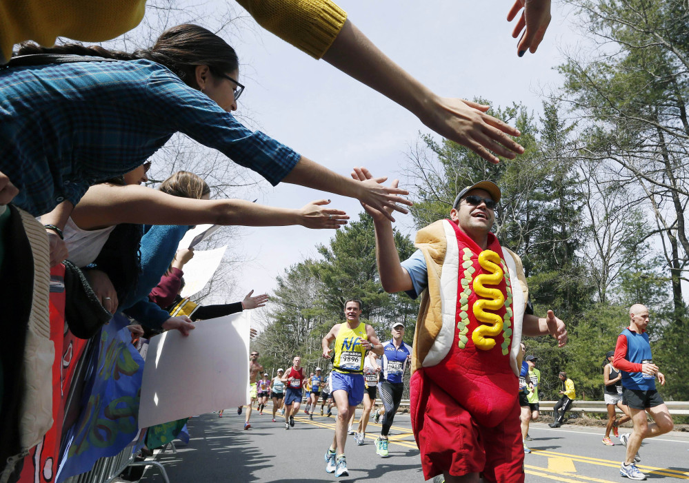 A man dressed as a hot dog runs through Wellesley, Mass., during last year’s Boston Marathon. Security will be tightened for the 2014 Boston Marathon after twin explosions killed three people and injured more than 260 near the finish line of the race in 2013. New rules include a limit on the size of water bottles, restrictions on bulky costumes, and nothing covering the face.