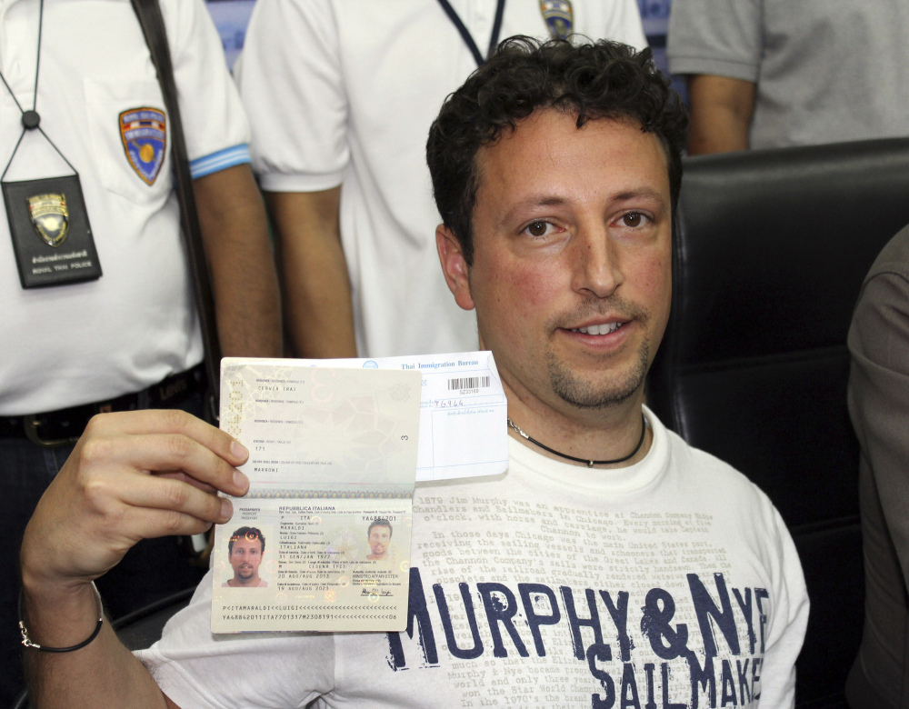 Italian Luigi Maraldi, left, whose stolen passport was used by a passenger boarding a missing Malaysian airliner, shows his passport as he reports himself to Thai police at Phuket police station in Phuket province, southern Thailand on Sunday. Maraldi spoke at a police news conference where he showed his current passport, which replaced the stolen one, and expressed surprise that anyone could use his old one.