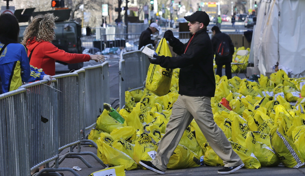 A worker returns a bag containing a runner’s personal effects near the finish line of the Boston Marathon on April 16, 2013, after bombs placed in backpacks killed three people.