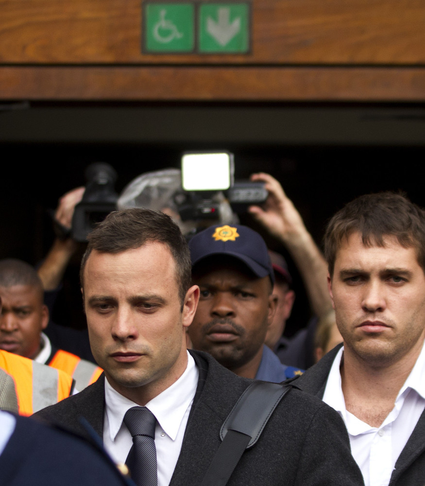 Oscar Pistorius, left, leaves the high court Tuesday in Pretoria, South Africa, Tuesday. He is charged with murder in the shooting death of his girlfriend in 2013.