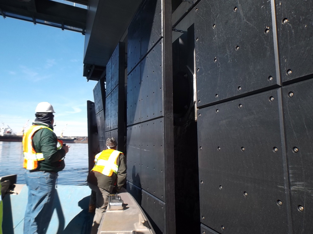 Engineers from the New Hampshire Department of Transportation get a close-up look at the damaged fender system that protects one of the piers on the Memorial Bridge. The system did its job when it was struck by a large tanker last Friday.