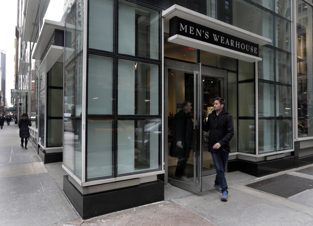 Two men exit a Men’s Wearhouse store in New York last week. Men’s Wearhouse will buy Jos. A. Bank Clothiers Inc. for $65 a share, the company announced Monday.
