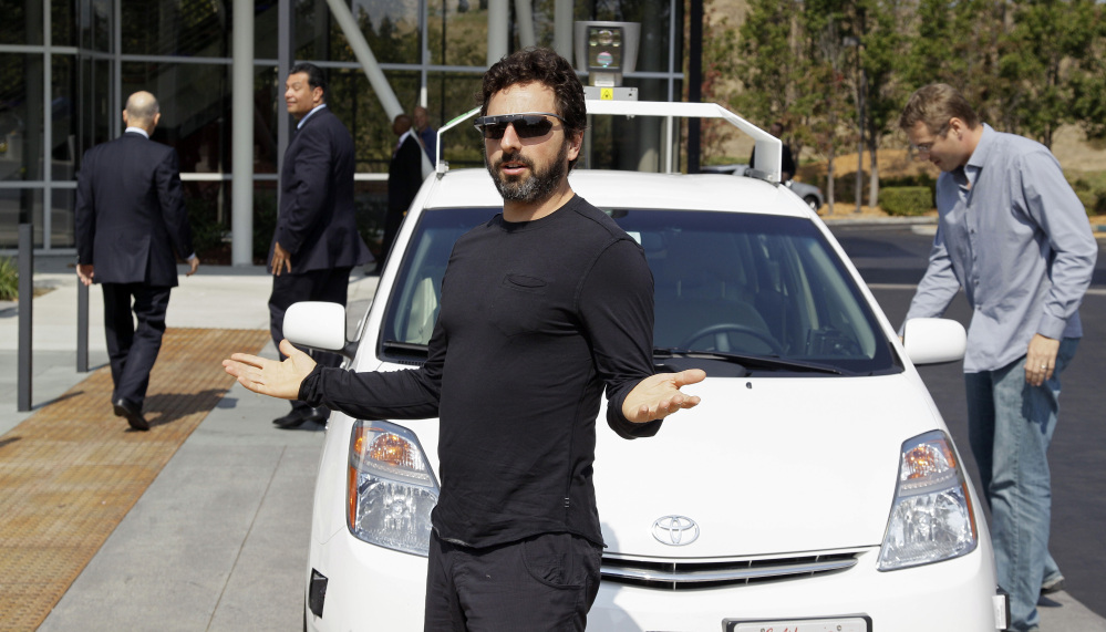 Google Inc. co-founder Sergey Brin exits a driverless car with California Gov. Edmund G. Brown Jr., walking away at left, as they head to the 2012 signing of a bill mandating that the state develop rules on public operation of the vehicles.