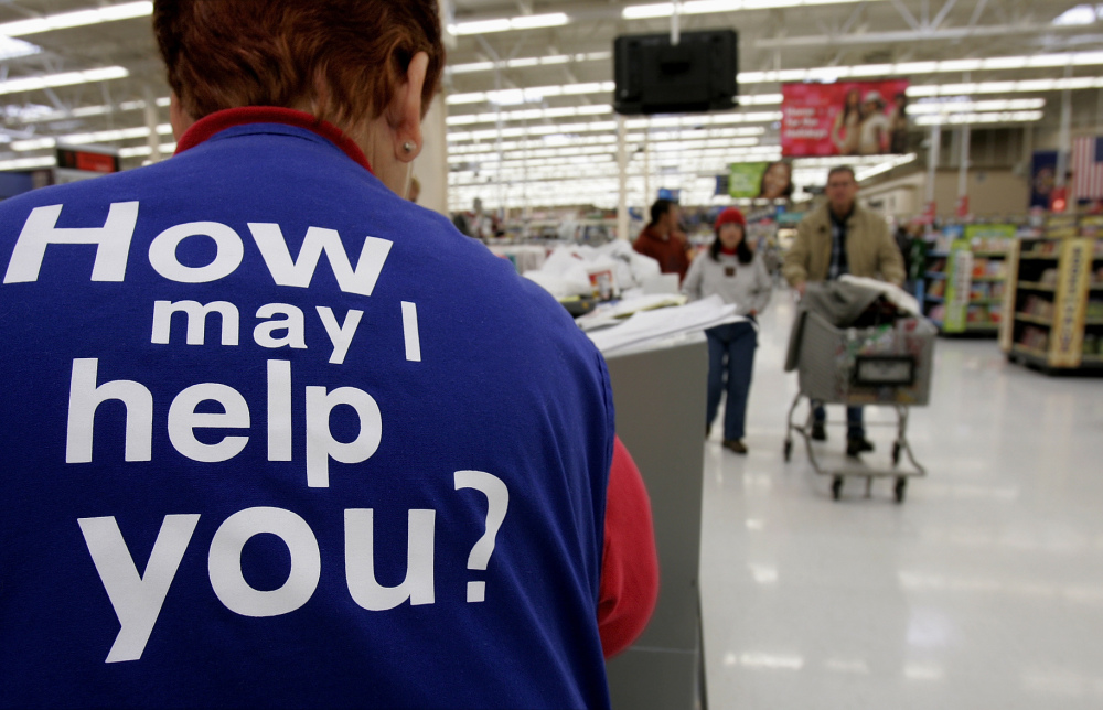 Customers at a Walmart store head to the checkout lines past a worker with the company’s motto on the back of her vest, in Salt Lake City. With fewer middle-income jobs available, low-wage work is becoming a dead-end for more Walmart employees.