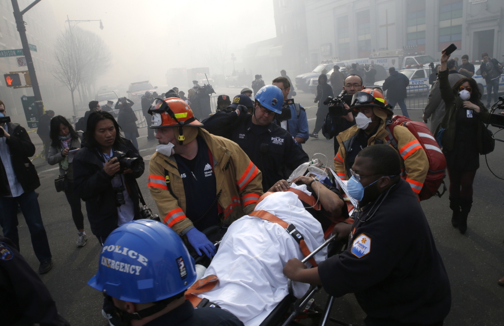 A victim is evacuated by emergency personnel near a building explosion in the Harlem section of New York City on Wednesday.