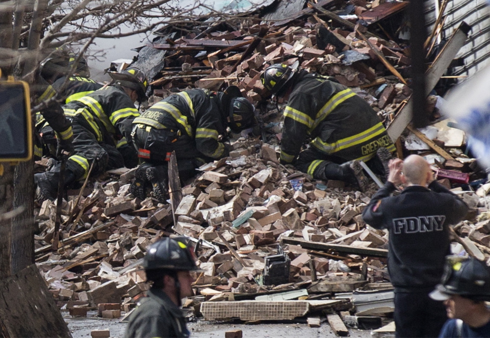 New York City firefighters dig through the rubble of a building explosion and collapse in East Harlem on Wednesday. Two apartment buildings collapsed, killing at least seven.