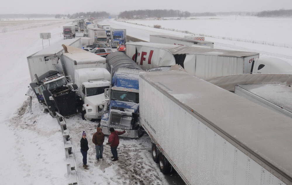 Truck drivers talk among themselves at the scene of an accident on the Ohio Turnpike northeast of Clyde, Ohio, after more than 50 vehicles crashed Wednesday. It was expected to be days before the road could be cleared.