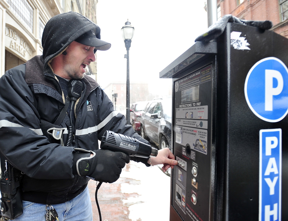 Tom Jarvais, parking meter supervisor for Portland, uses a hand-held heat gun Thursday to thaw out the frozen buttons on one of the new solar-powered pay-to-park stations on Exchange Street. The city invested $465,000 in the machines, which accept debit and credit cards in addition to coins, and are meant to take the place of coin-only meters. Thursday’s incident was the second time the units malfunctioned this winter.