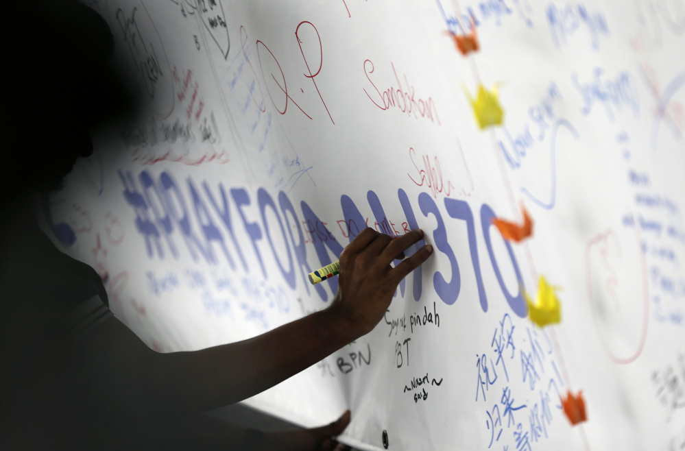 A man writes messages and well wishes on a banner dedicated to all involved with the missing Malaysia Airlines jetliner MH370 at the Kuala Lumpur International Airport on Thursday.