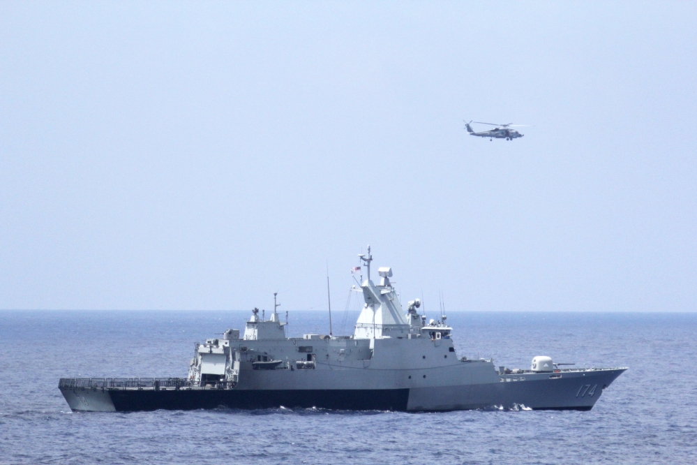 The Royal Malaysian Navy corvette KD Terengganu and a U.S. Navy MH-60R Sea Hawk helicopter conduct a coordinated air and sea search for a missing Malaysian Airlines jet in the Gulf of Thailand.