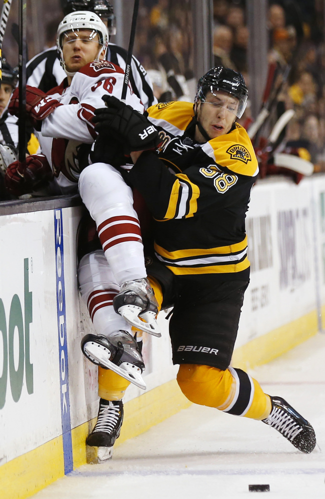 Boston Bruins’ Jordan Caron checks Phoenix Coyotes’ Rob Klinkhammer into the boards in the third period Thursday.