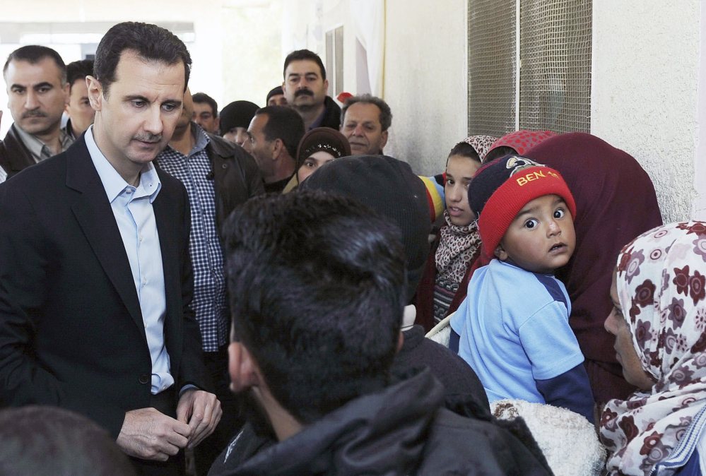 Syria’s President Bashar Assad speaks with children during his visit to displaced Syrians in the town of Adra in the countryside outside Damascus on Wednesday.