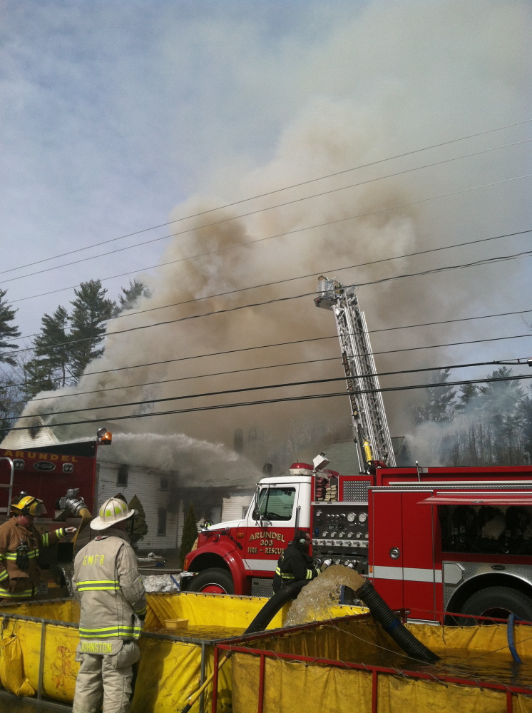 Firefighters pump water to fight a house fire in Arundel on Friday.