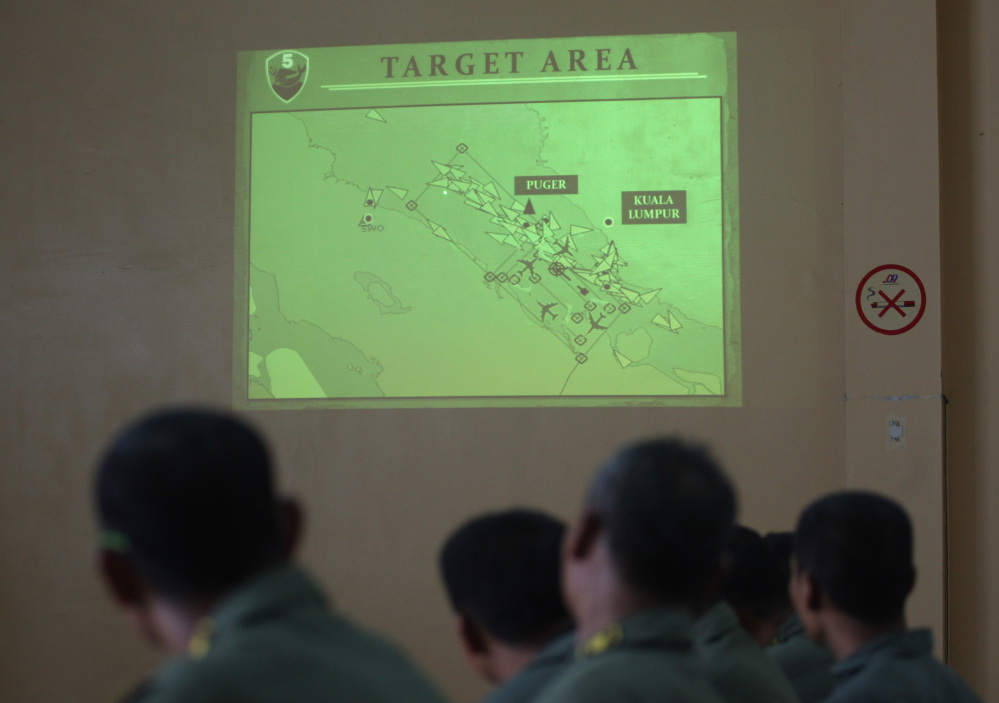 Indonesian Air Force personnel of the 5th Air Squadron “Black Mermaids” listen to a briefing as an operation map is projected on the wall following a search mission for the missing Malaysia Airlines Boeing 777.