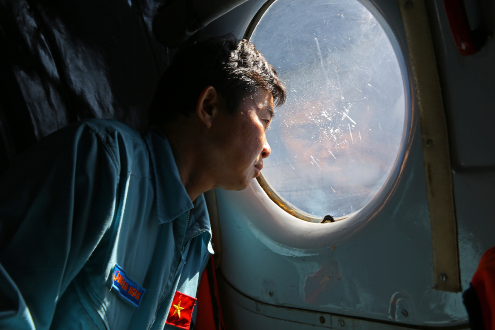 Officer Lang Van Ngan of the Vietnam Air Force looks out the window of an AN-26 Soviet made aircraft during a search operation for the missing Malaysia Airlines flight MH370 plane over the southern sea between Vietnam and Malaysia Friday.