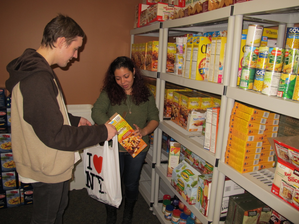 Stony Brook University students Ruby Escalera-Nater and Will Addison fill a bag of food to give to guests at the college’s recently opened food pantry. Officials say there are a growing number of food pantries opening on college campuses across the country to assist students contending with rising education costs.