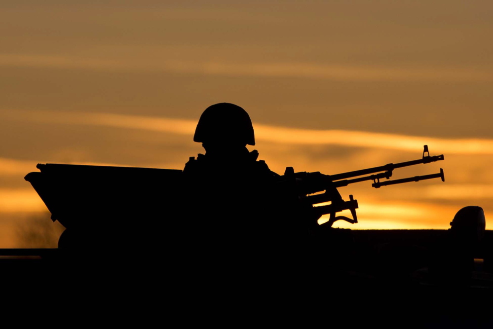A pro-Russian soldier is silhouetted by the sunset sky as he mans a machine gun outside a Ukrainian military base in Perevalne, Ukraine, on Saturday. Tensions are high in the Black Sea peninsula of Crimea, where a referendum is to be held Sunday on whether to split off from Ukraine and seek annexation by Russia.