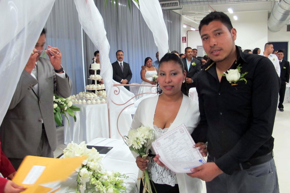 One of 31 couples who married on Valentine’s Day at a mass wedding at the Plantronics factory pose as they receive a certificate.