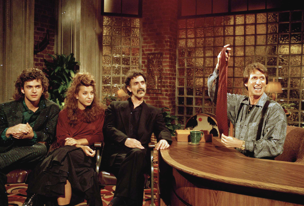 Comedian David Brenner hosts avant garde fusion musician Frank Zappa, center, and his children, Dweezil, left, and Moon Unit during a taping of his “Nightlife” talk show in New York in 1986.