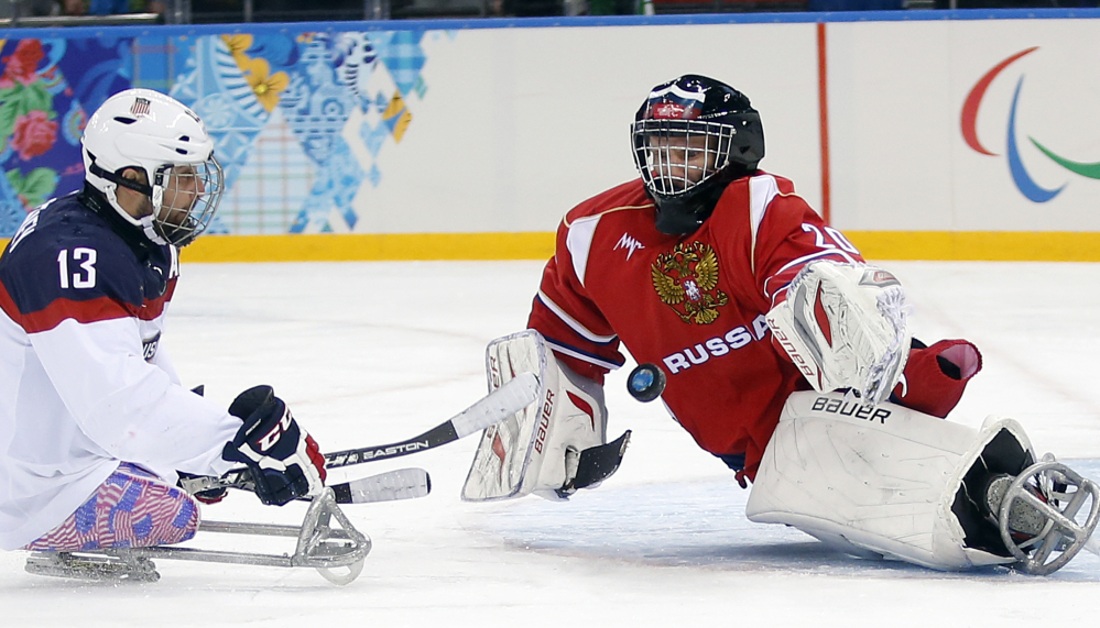 United States’ Joshua Sweeney, left, shoots on goal as Russia’s Vladimir Kamantcev, right, tries to defend during the gold medal ice sledge hockey game Saturday at the 2014 Winter Paralympics in Sochi, Russia. The U.S. won, 1-0.