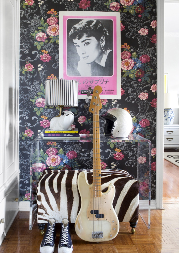 Floral wallpaper is contrasted with modern furniture and unexpected accessories like a bike helmet and a vintage Japanese poster for the movie “Sabrina,” to create a fresh and edgy look.
