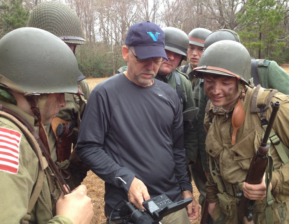 Director of photography Jerry Hattan reviews footage with re-enactors portraying American troops on D-Day.