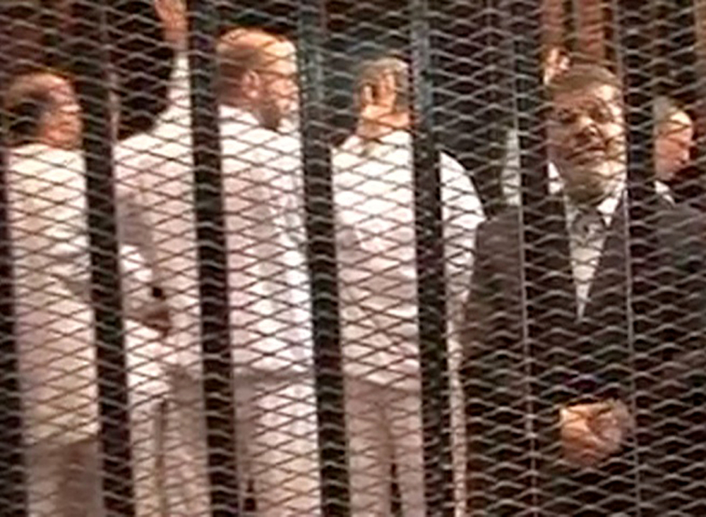 Mohammed Morsi, right, speaks from the defendant’s cage as he stands with co-defendants in a makeshift courtroom during a hearing in November in Cairo. Egypt’s crackdown on Islamists since Morsi was ousted as president has jailed 16,000 people over the past eight months, according to security officials.