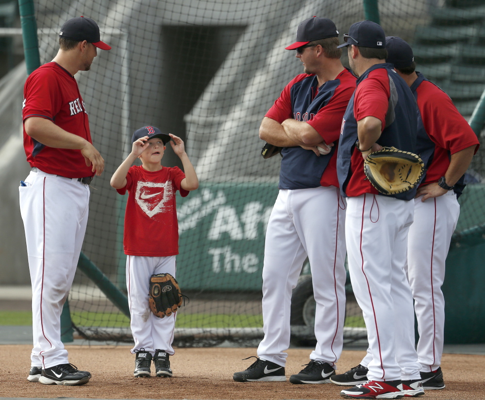 Austin Pierzynski, center left, son of Red Sox catcher A.J. Pierzynski, right, tries on his hat before Red Sox batting practice in Fort Myers, Fla., Monday.