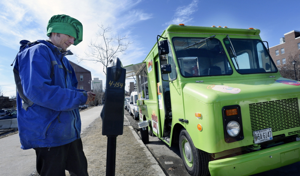 James Dinsmore of Wicked Good Truck feeds the parking meter Monday. The food truck’s owner wants Portland’s ordinance changed.