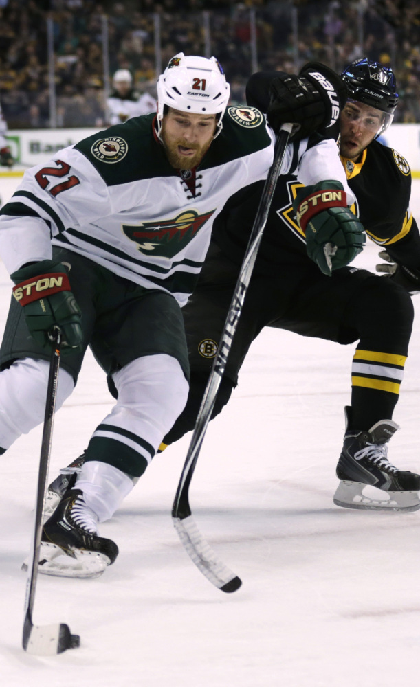 Boston Bruins center Gregory Campbell, right, chases Minnesota Wild center Kyle Brodziak (21) during the first period of an NHL hockey game, Monday, March 17, 2014, in Boston. (AP Photo/Charles Krupa)