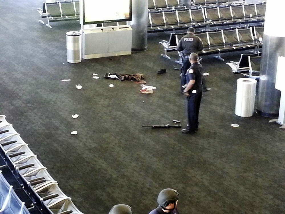 In this Nov. 1, 2013 file photo police officers stand near a weapon at the Los Angeles International Airport after a gunman opened fire in the terminal, killing one person and wounding several others. Thousands of Los Angeles International Airport workers had no idea what to do when a gunman opened fire last year or how to help because they were inadequately trained to deal with an emergency.