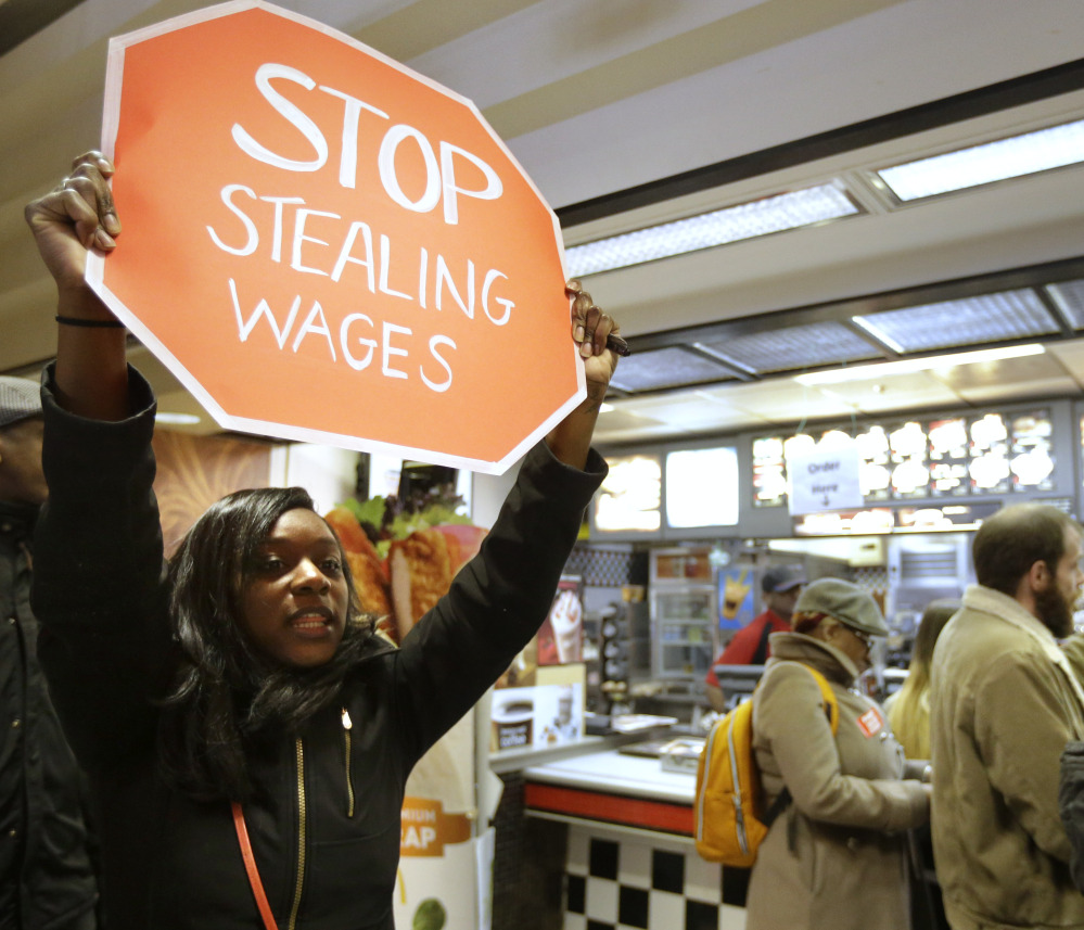 Demonstrator Sherae Speight holds a placard and chants during a protest at a McDonald’s restaurant in Boston Tuesday. Protesters wanted to call attention to the denial of overtime pay and other wages workers say the company owes its workers.