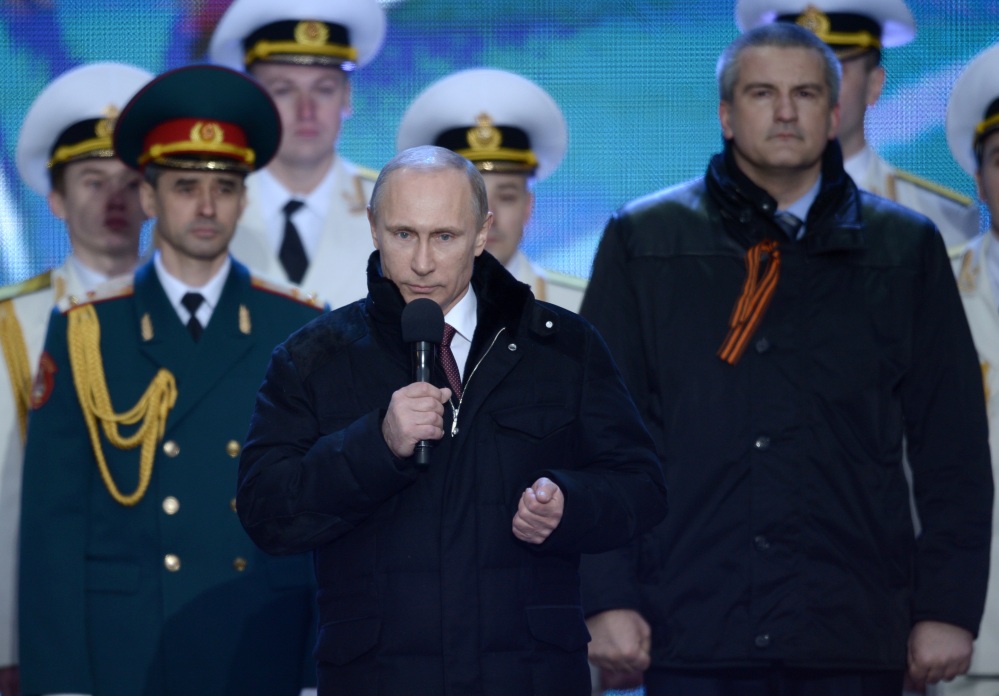 Russian President Vladimir Putin speaks at a rally in support of Crimea joining Russia, in Red Square Tuesday. With a sweep of his pen, Putin added Crimea to the map of Russia, describing the move as correcting past injustice and responding to what he called Western encroachment upon Russia’s vital interests. At right is Crimean Premier Sergei Aksyonov.
