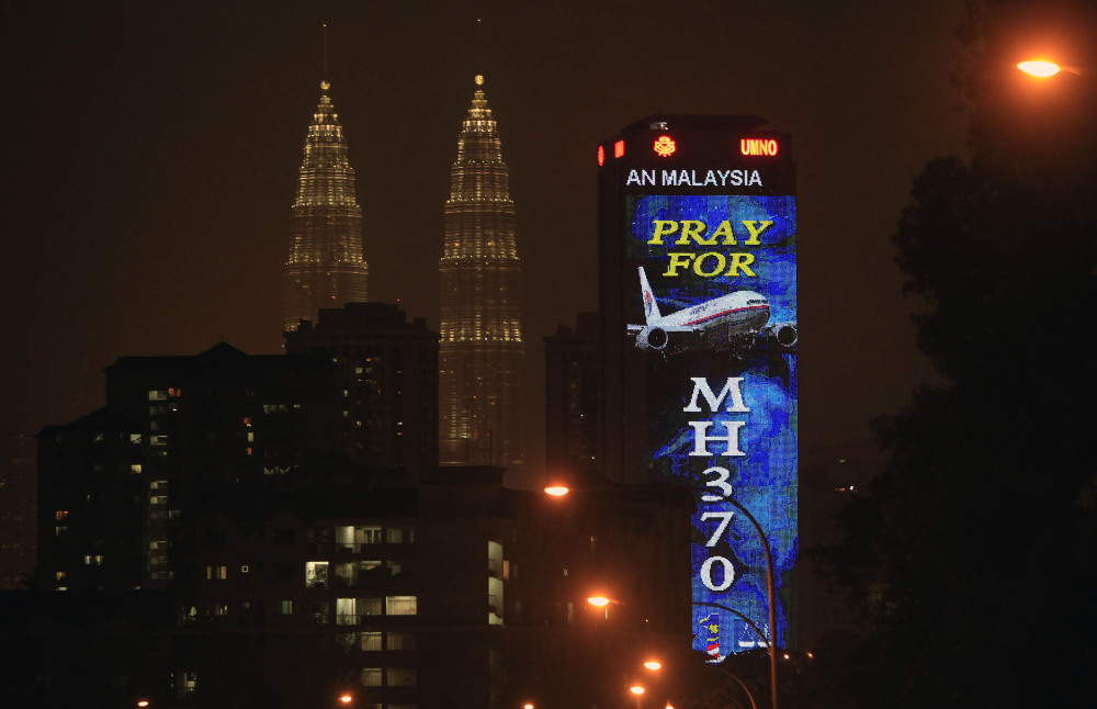 An office building is illuminated with LED lights displaying “Pray for MH370” next to Malaysia’s landmark Petronas Twin Towers in Kuala Lumpur, Malaysia, Wednesday, March 19, 2014. Investigators are trying to restore files deleted last month from the home flight simulator of the pilot aboard the missing Malaysian plane to see if they shed any light on the disappearance, Malaysia’s defense minister said Wednesday.
