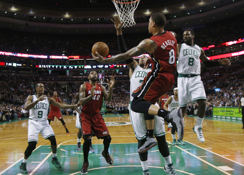 Miami Heat forward Michael Beasley leaps behind the basket to make a play as Boston Celtics center Jared Sullinger (7) and forward Jeff Green (8) defend in the first quarter Wednesday in Boston.