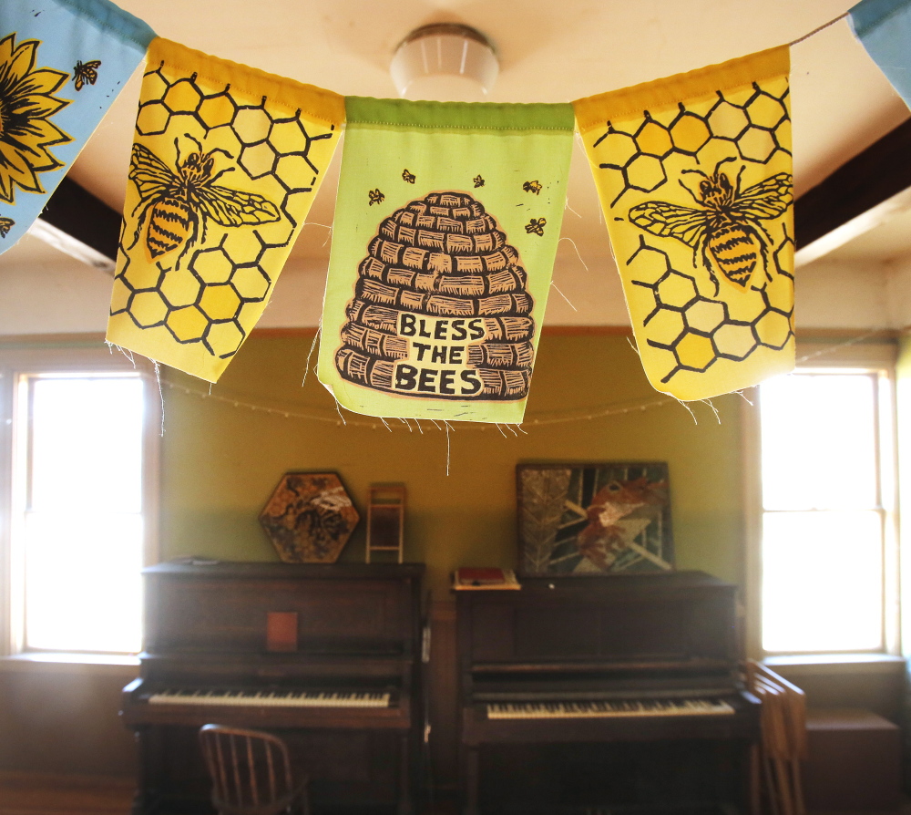 Homemade flags hang from the ceiling on the second floor of the Grange, one saying "Bless the Bees."