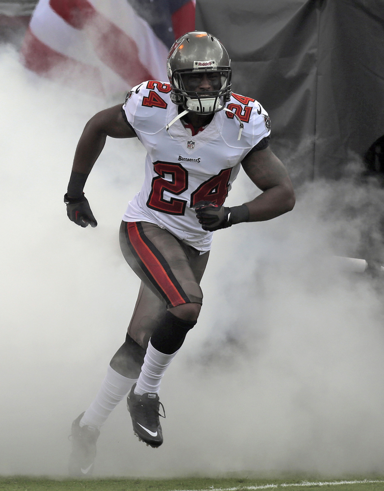 Cornerback Darrelle Revis runs through smoke during Tampa Bay Buccaneers introductions last September. The New England Patriots have since signed Revis, whom Tampa Bay released.