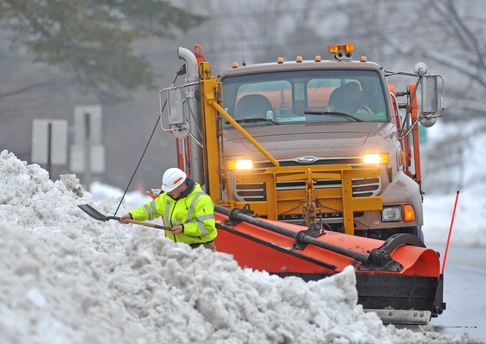 Drew Veilleux with the Maine DOT shovels snow from the side of Route 201 in Hinkley with his plow waiting behind him Thursday. Crews worked to help with drainage issues.