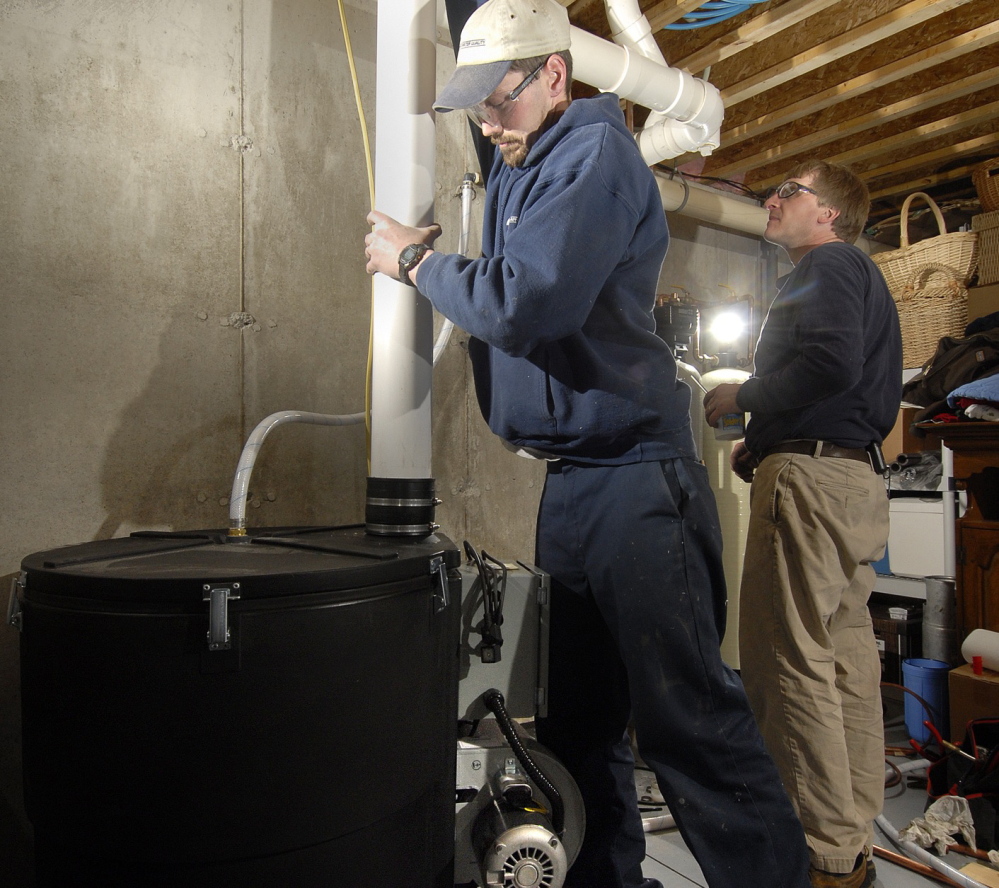 Shawn Garrity, left, and Scott King of Air & Water Quality, Inc. of Freeport install a radon gas treatment unit in a Maine home in 2007. Maine law requires landlords to test for radon in all buildings with rental units – but it’s still unclear what agencies will enforce the penalties if they don’t.