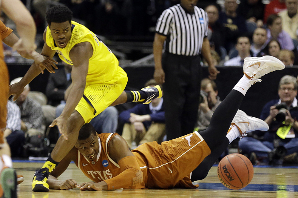 Michigan guard Derrick Walton Jr., left, and Texas forward Jonathan Holmes chase after a loose ball during the second half of a third-round game of the NCAA college basketball tournament Saturday.