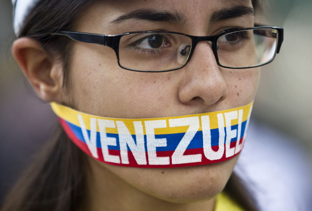 An anti-government demonstrator stands with a tri-colored ribbon covering her mouth that reads “Venezuela” during a protest in front of an office of the Organization of American States, OAS, in Caracas, Venezuela, on Friday.
