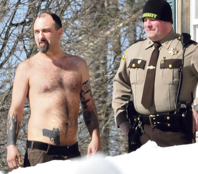 Norridgewock resident Michael Smith stands beside a Somerset County sheriff’s deputy after he was coaxed out of his home Tuesday.