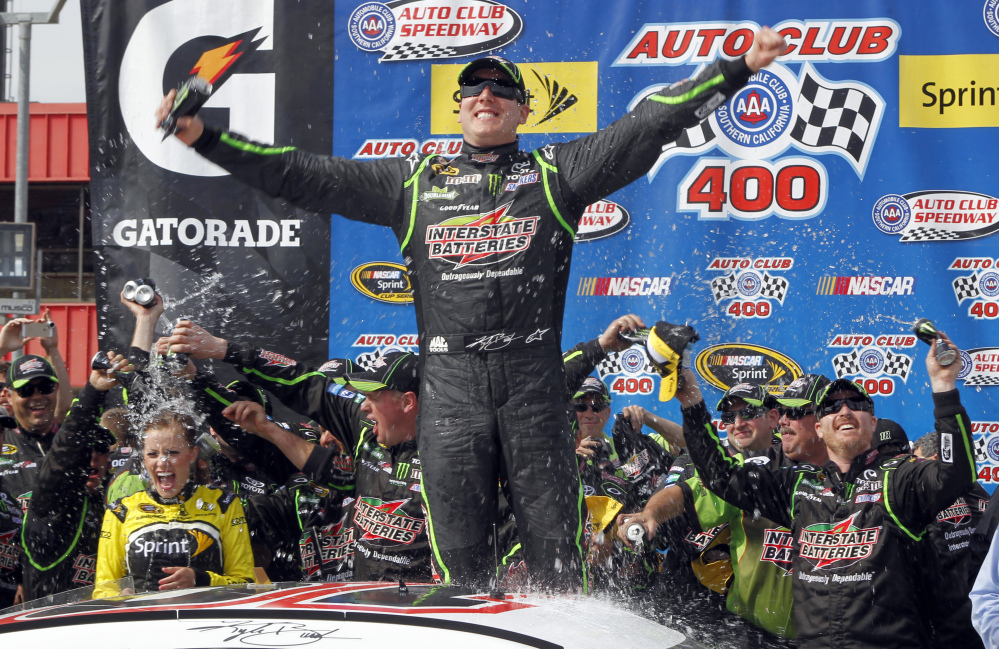 Kyle Busch, center, celebrates, in the victory circle after winning the NASCAR Sprint Series auto race in Fontana, Calif., on Sunday.