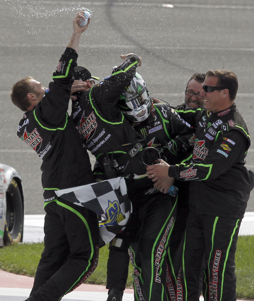 A helmeted Kyle Busch finds himself the center of attention as members of team celebrate after his first-place finish at Fontana, Calif., on Sunday.