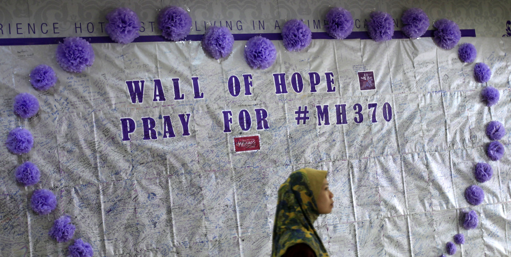 A woman walks past a message board for passengers aboard a missing Malaysia Airlines plane, at a shopping mall in Kuala Lumpur, Malaysia, Sunday.