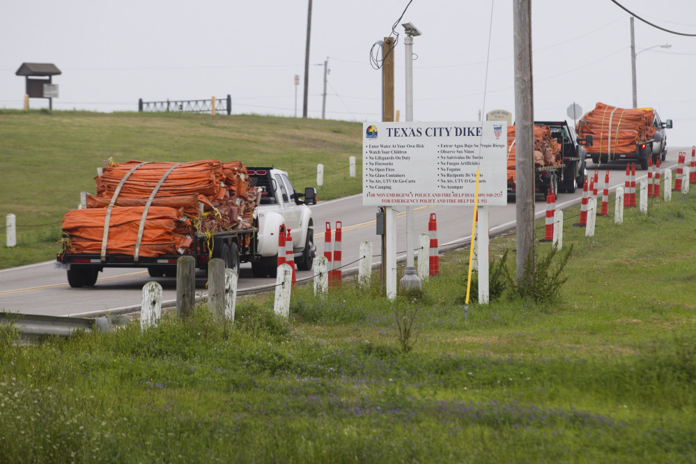 Environmental personnel drive onto the Texas City Dike with oil containment booms for oil remediation following a barge collision in the ship channel, causing an oil spill on Saturday. The barge carried 924,000 gallons of fuel oil.